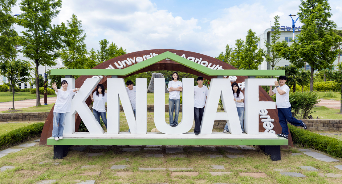 한국농수산대학교 로고(KNUAF) 앞에서 학생 7명이 각자 사진 촬영 포즈를 취하고 있는 모습